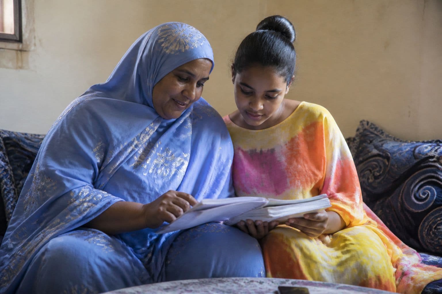 أم وابنتها تراجعان الدفاتر المدرسية معاً